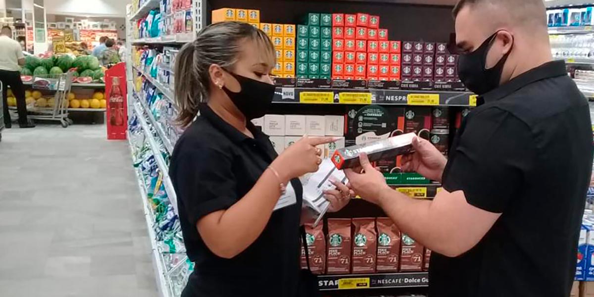 mulher mostrando produto para homem em supermercado em uma ação promocional