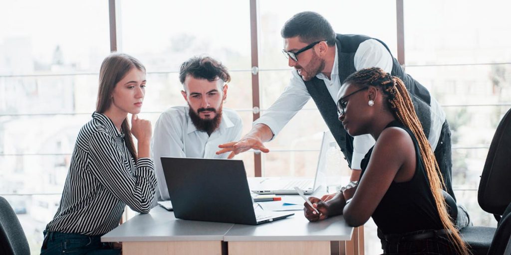 homem orientando três colaboradores em escritório aplica a gestão estratégica de pessoas para ter uma equipe de sucesso