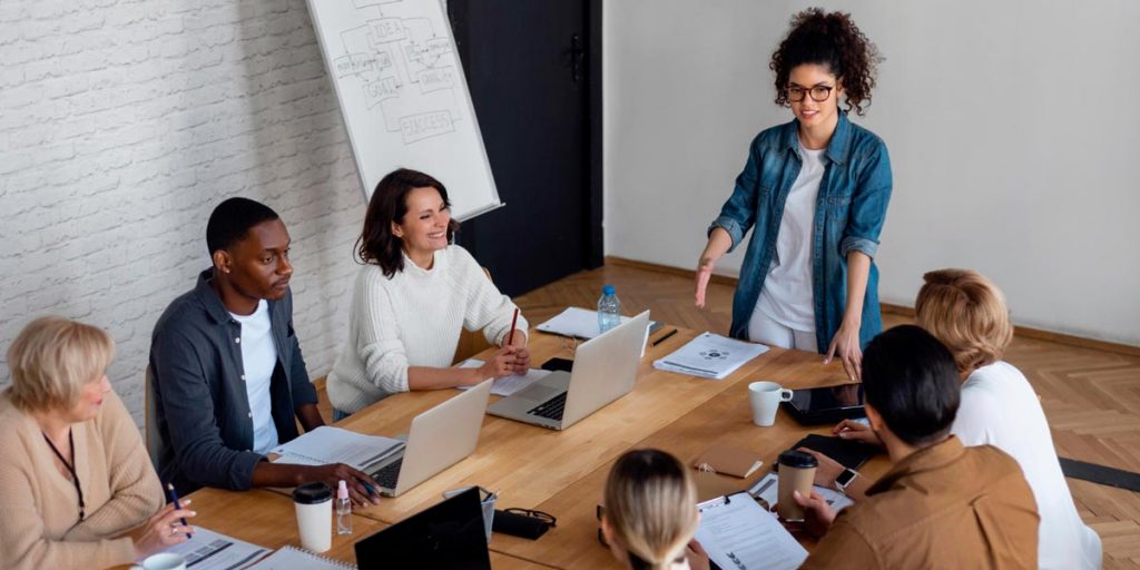 gestora e colaboradores em sala de reunião sabe como motivar a equipe